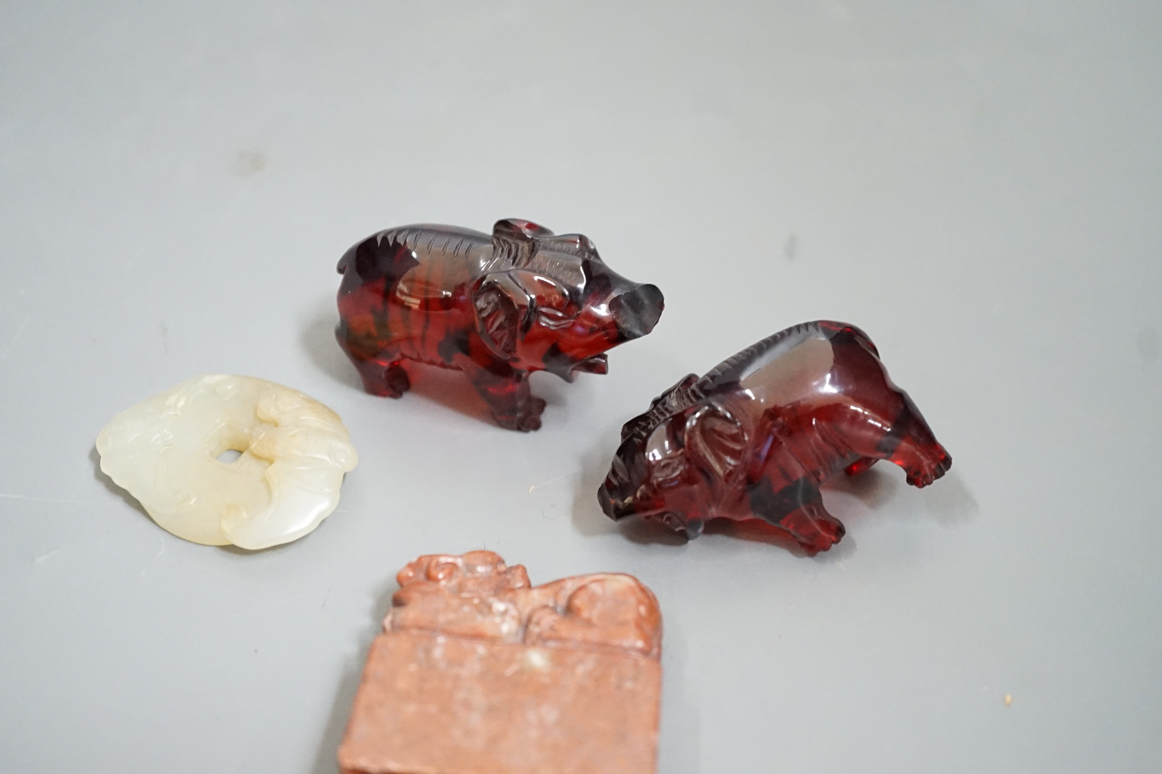 A Chinese Jade bi disc, two cherry amber ox and a soapstone seal